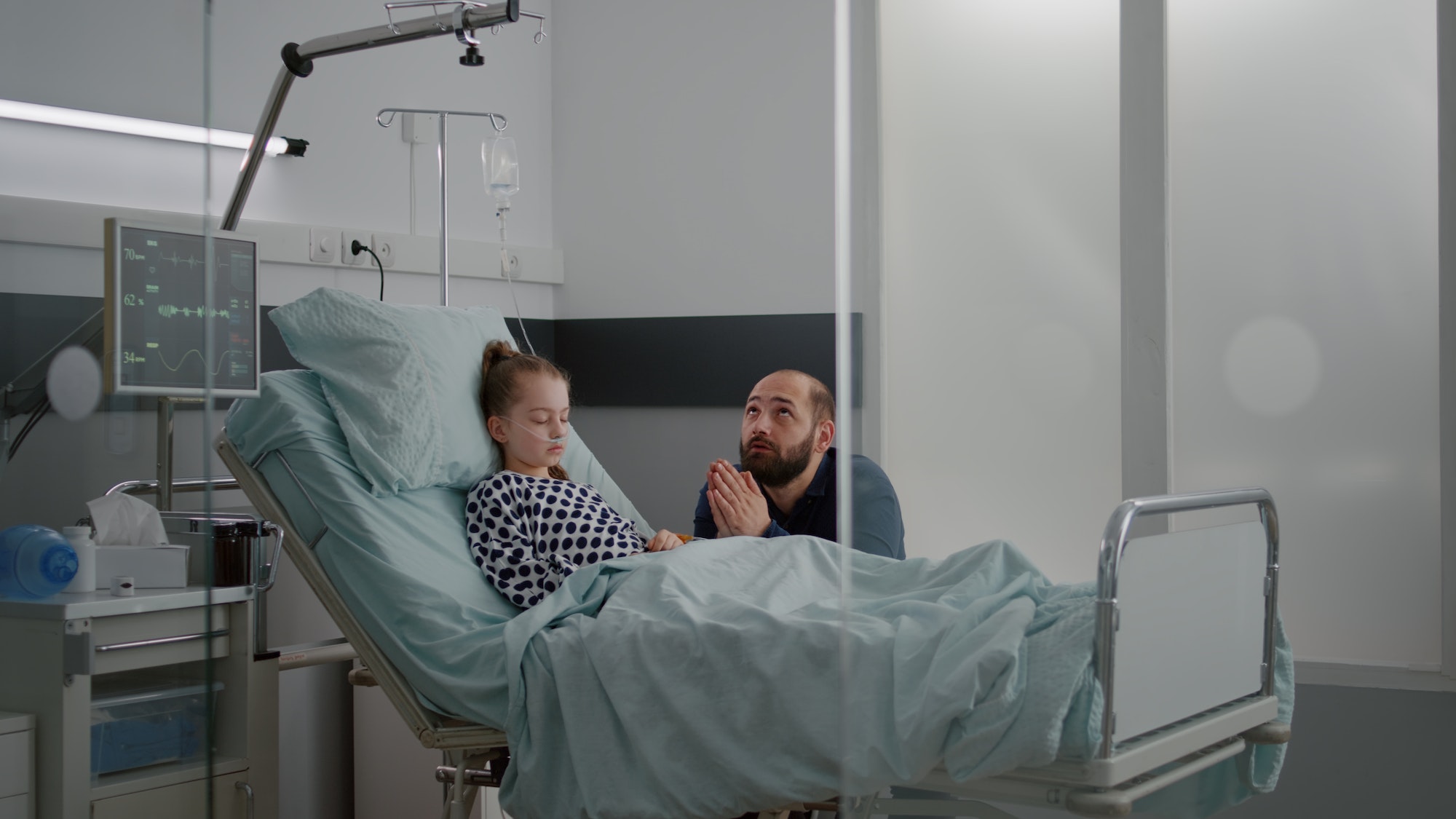 Worried sad father holding hands together praying while waiting sickness diagnose